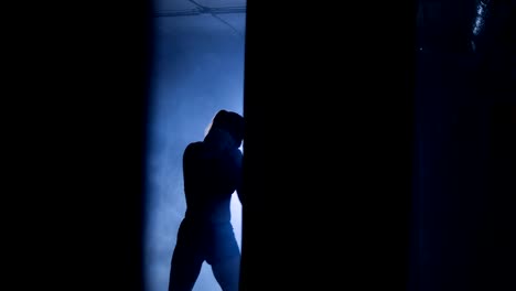 Silhouettes-of-a-woman-boxer-trains-in-dark-gym