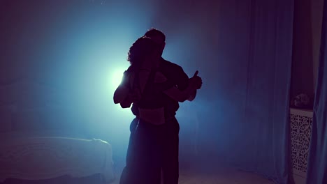 Young-couple-dancing-latin-music.-Silhouette-couple-ballroom.-Smoke