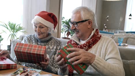 Senior-Couple-Opening-Christmas-Gifts-at-Holiday-Dinner-in-Cafe