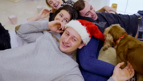 Four-friends-and-dog-relax-near-Christmas-tree