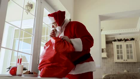 Santa-Claus-gusto-galletas-y-regalos-puso-de-su-bolsa-de-sobre-mesa