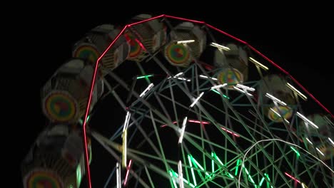 Carnival-with-ferris-wheel,-bright-colourful-lights,-car-carousel-at-night-closeup