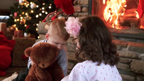 Siblings-reading-a-book-at-fireplace