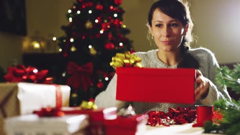 Muchacha-con-sombrero-de-la-Navidad-hace-deseos-y-abre-un-paquete-de-regalo-de-Navidad.-concepto-de-vacaciones-y-año-nuevo.-la-niña-es-feliz-y-sonríe-de-la-mano-con-el-regalo-de-Navidad.