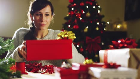 Mädchen-mit-weihnachtsmütze-macht-Wünsche-und-öffnet-ein-Weihnachts-Geschenk-Paket.-Konzept-der-Feiertage-und-Neujahr.-Das-Mädchen-freut-sich-und-lächelt-mit-Weihnachts-Geschenk-in-der-hand.