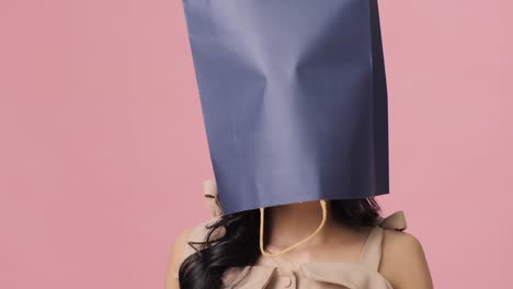 Female-shopper-with-shopping-bags-over-heads.-Portrait-of-female-posing-at-camera-on-pink-background-with-copy-space.