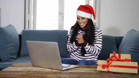 Frau-mit-roten-Pullover-und-Weihnachtsmann-Mütze-mit-Kreditkarte-auswählen-und-kaufen-Weihnachtsgeschenke-mit-Laptop-zu-Hause-begeistert-mit-Verkauf-über-das-Internet-und-Kreditkarte-Einrichtungen-in-Linie-einkaufen