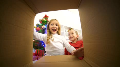 Glückliche-Kinder-öffnen-Sie-das-Feld-neben-dem-Weihnachtsbaum