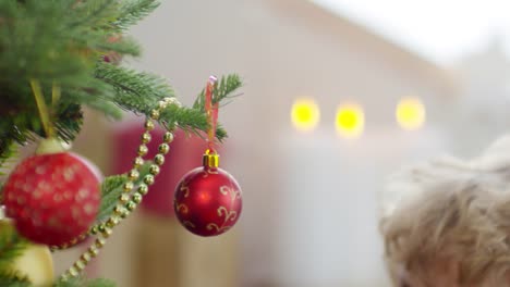 Lockige-jungen-und-Mutter-schmücken-Weihnachtsbaum