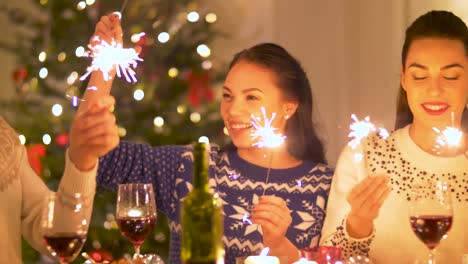 happy-friends-with-sparklers-having-christmas-dinner-at-home