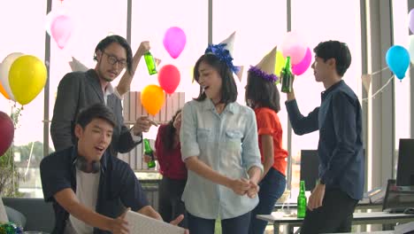 Team-of-young-people-dancing-and-having-fun-celebrate-with-toast-and-clinking-raising-glasses-in-their-office.-Slow-motion-shot