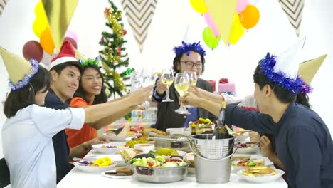 Gruppe-von-Asiaten-zusammen-am-Tisch-Toasten-und-Weihnachten-mit-leckeren-Essen-an-Silvester-Party-zu-feiern.-Menschen-mit-Urlaub-und-Feier-Konzept.