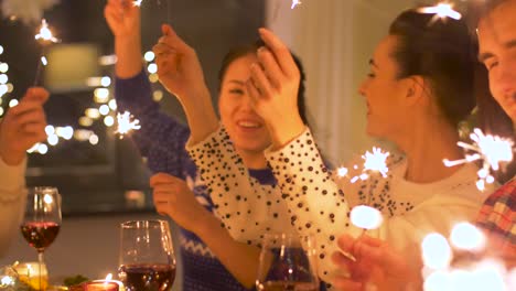 happy-friends-with-sparklers-having-christmas-dinner-at-home