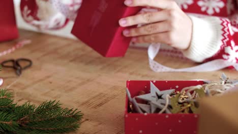 Cerca-de-las-manos-de-la-mujer-envolviendo-los-regalos-de-Navidad