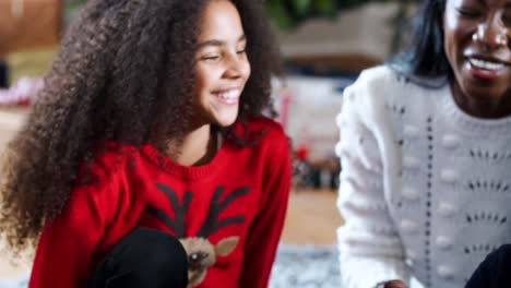 Aufgeregten-Kinder-sitzen-am-Boden-mit-Mutter-als-Familie-gemeinsam-Weihnachten-feiern