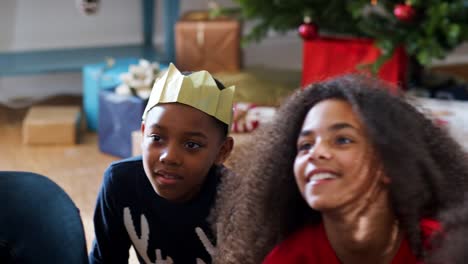 Excited-Children-Sit-On-Floor-With-Mother-As-Family-Celebrate-Christmas-Together