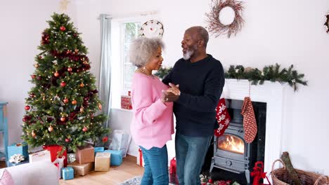 Ältere-schwarze-Paare-tanzen-in-ihrem-Wohnzimmer-dekoriert-für-Weihnachten,-Dreiviertel-Länge-Ansicht,-handheld