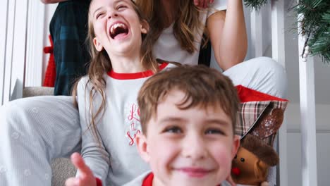 Porträt-von-aufgeregt-Familie-tragenden-Pyjamas-sitzt-auf-der-Treppe-am-Weihnachtsmorgen