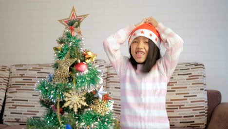 Asian-little-girl-decorating-a-Christmas-tree-and-dancing-with-happiness