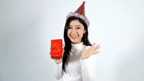 mujer-joven-feliz-con-sombrero-y-sosteniendo-una-caja-de-regalo-de-Navidad-Roja-sobre-un-fondo-blanco