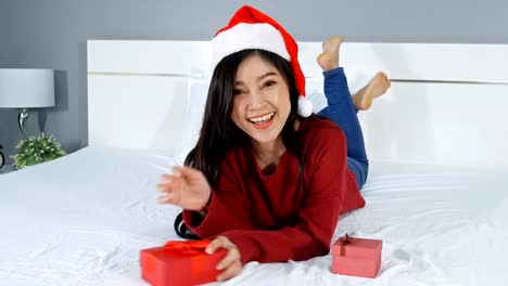 glückliche-Frau-hält-Weihnachtsgeschenk-auf-einem-Bett