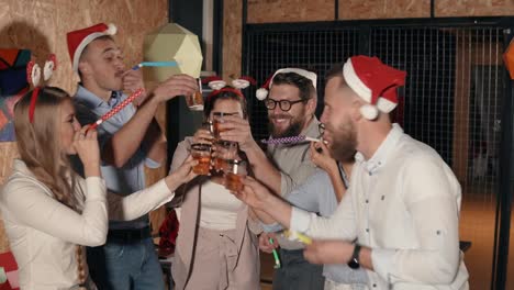 Happy-friends-are-celebrating-Christmas-together,-blowing-party-blowouts