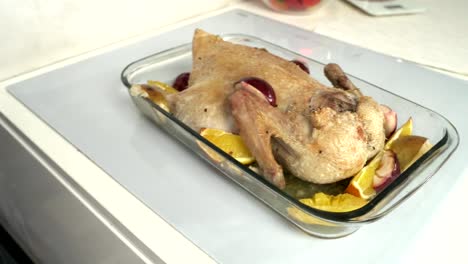 Woman's-hands-spread-by-marinade-raw-goose,-stuffed-sliced-apples.-Goose-prepare-for-cooking-in-baking-dish-with-ripe-apples-over-table-with-white-tablecloth.-Day-light