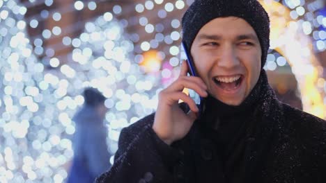 Junger-Mann-am-Telefon-zu-sprechen,-in-der-Weihnachtsnacht-auf-der-Straße