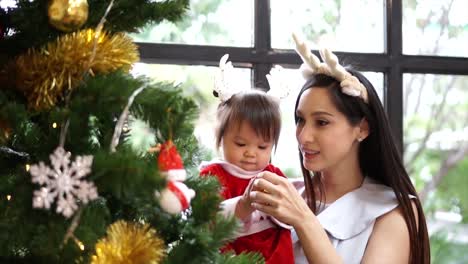 Tochter-von-Mutter-und-Kind-schmücken-den-Weihnachtsbaum-im-Innenbereich.-Closeup-Zeitlupe-Porträt-des-liebenden-Familie,-Frohe-Weihnachten-und-schöne-Feiertage!