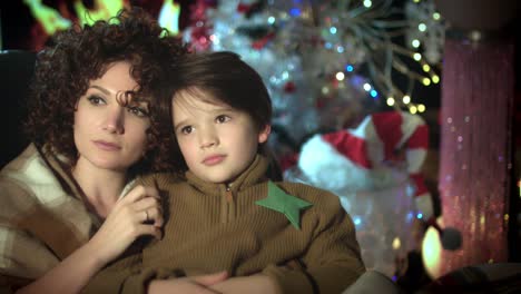 4k-Christmas-and-New-Year-Holiday-Child-and-his-Mom-Daydreaming-at-Fireplace