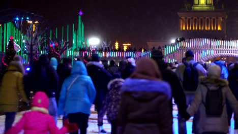 Deporte-de-invierno-de-concepto.-Multitud-en-la-pista-de-patinaje-de-noche.-Nieve-que-cae.-Estrella-de-Navidad