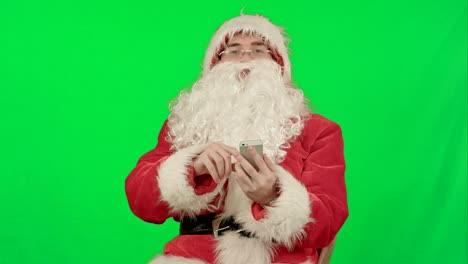 santa-claus-liest-und-sendet-Textnachrichten-von-seinem-Handy-auf-einem-Green-Screen-Chrome-Key