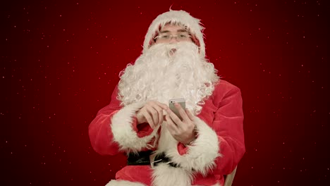 santa-claus-reads-and-sends-text-messages-from-his-cell-phone--on-red-background-with-snow