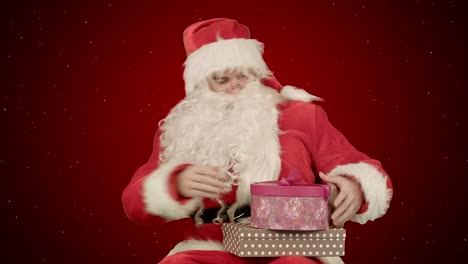 Santa-Claus-holding-a-gift-in-his-hand-on-red-background-with-snow