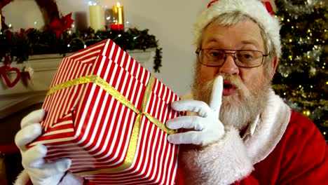 Porträt-des-Weihnachtsmannes-halten-Geschenkbox-mit-Finger-auf-die-Lippen