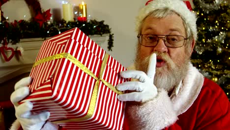 Retrato-de-santa-claus-con-caja-de-regalo-con-el-dedo-en-los-labios