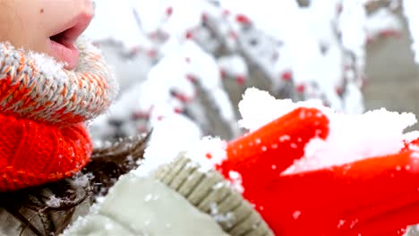 Close-up-of-girl-in-red-scarf-and-gloves-blowing-snow