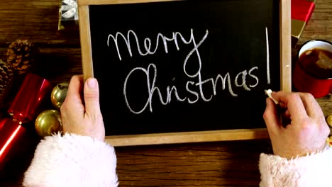 Santa-claus-writing-merry-christmas-on-slate