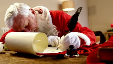 Papá-Noel-durmiendo-en-el-escritorio-mientras-escribía-una-carta-con-una-pluma