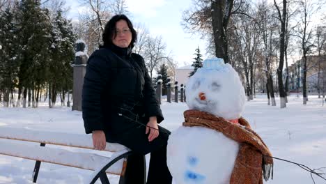 Joven-mujer-edificio-muñeco-de-nieve-en-el-parque.-En-el-invierno