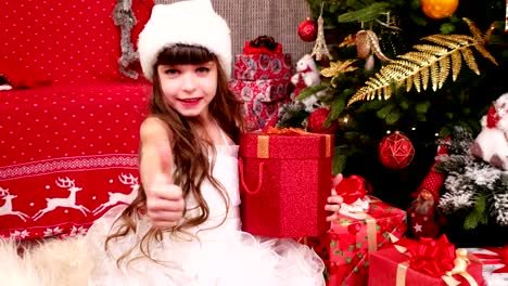 child-enjoys-the-gifts-for-Christmas,-Little-girl-plays-with-gifts-in-the-house-on-Christmas-Eve,-child-carnival-costume-near-the-Christmas-tree,-winter-holiday-of-New-Year