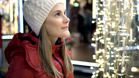 Schöne-attraktive-Frau-stehen-in-der-Nähe-ein-Window-shop-mit-Garnands-verziert.-Neues-Jahr-Weihnachten