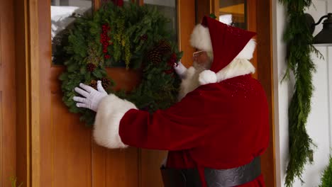 Santa-Claus-putting-wreath-on-door