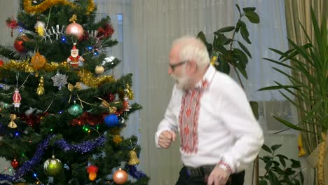 Old-cheerful-man-dances-near-the-christmas-tree