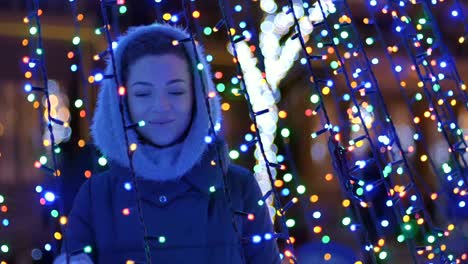 Portrait-of-cute-girl-touches-a-colorful-lamp-of-garland