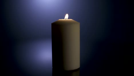 Slow-motion-macro-footage-of-a-white-candle-on-a-dark-background