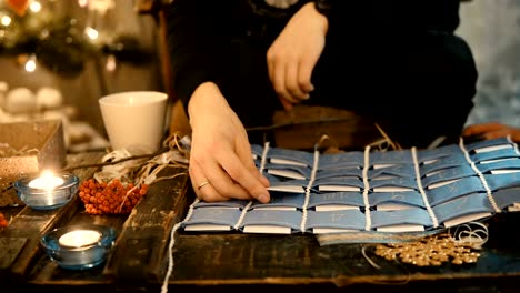 Close-up-view-of-young-couple-sitting-at-the-table-in-evening-and-open-the-advent-calendar-together,-drinking-tea