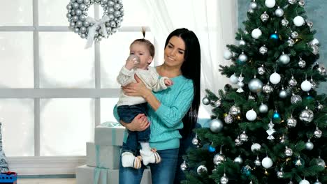 Mutter-mit-ihren-10-Monate-alten-Baby-Girl-dekorieren-Weihnachtsbaum-im-Wohnzimmer