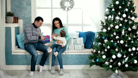 Beautiful-christmas-happy-family-with-little-girl-in-knitted-sweaters-sitting-on-the-windowsill