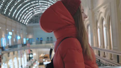 beautiful-young-woman-with-a-broad-smile-is-walking-through-the-big-shopping-mall-in-Moscow